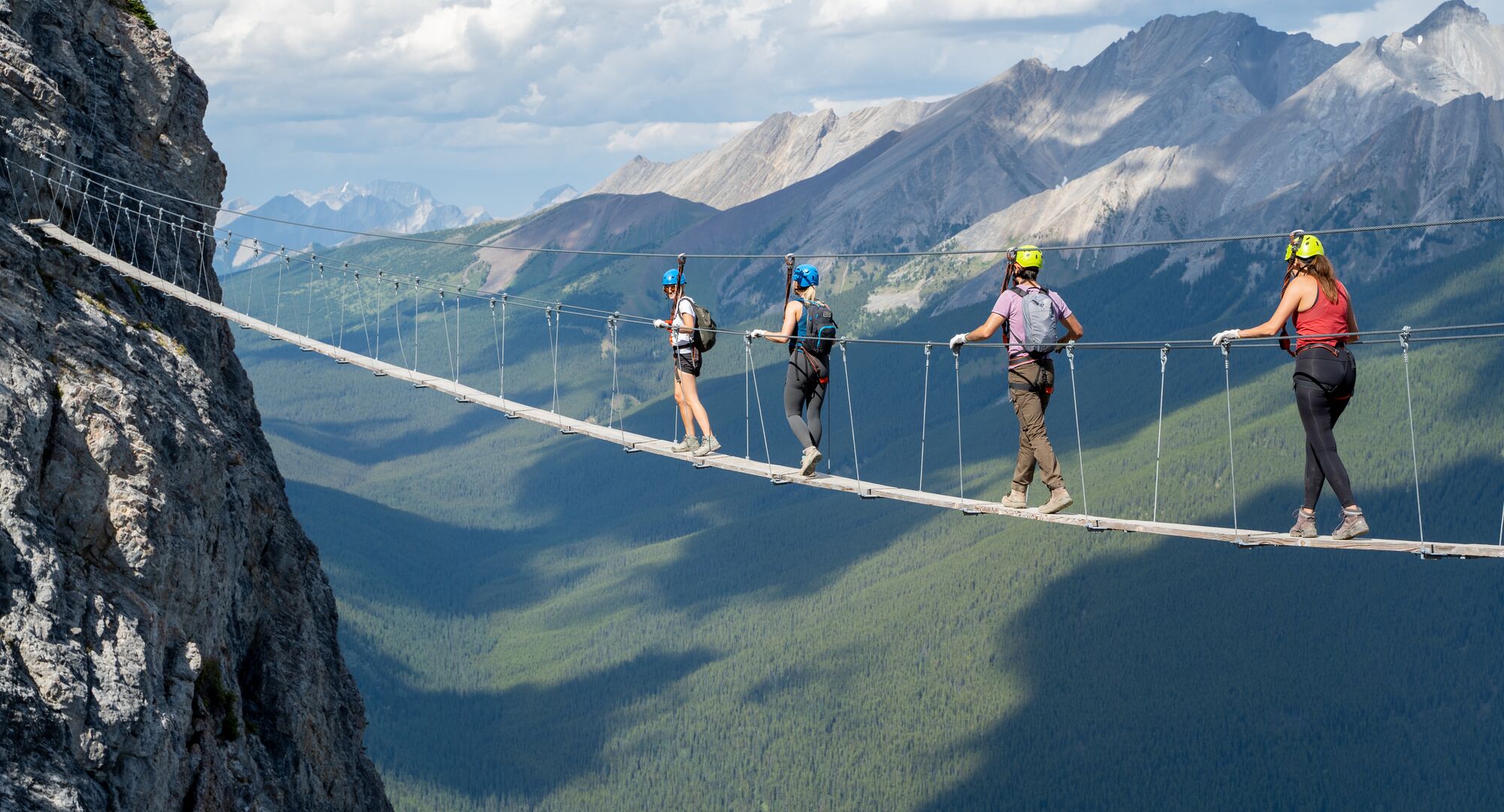 A group of people crossing a wooden suspension bridge at the Mt. Norquay Via Ferrata